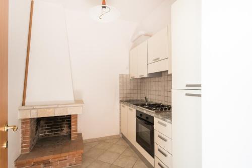 a kitchen with white cabinets and a brick fireplace at Residenza Piccolo Uliveto in San Menaio