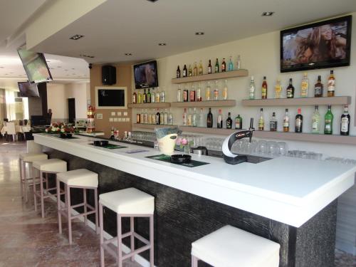 un bar avec des tabourets blancs et un comptoir avec de l'alcool dans l'établissement Morfeas Hotel, à Kavos