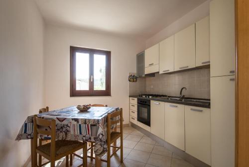 una cucina con tavolo e sedie e una cucina con armadietti bianchi di Residenza Piccolo Uliveto a San Menaio