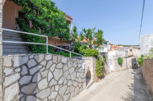 a stone wall next to a house with a staircase at Rooms Roza in Vrboska