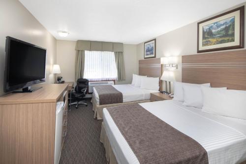 a hotel room with two beds and a flat screen tv at Travelodge by Wyndham Golden Sportsman Lodge in Golden