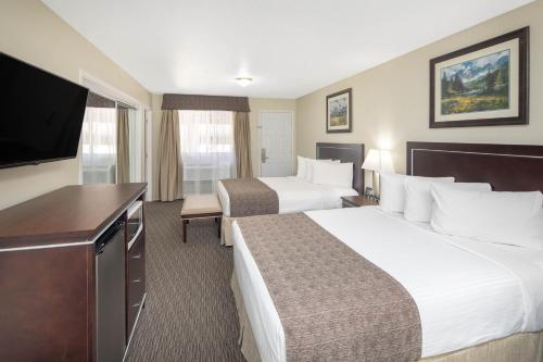 a hotel room with two beds and a flat screen tv at Travelodge by Wyndham Golden Sportsman Lodge in Golden