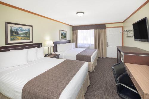 a hotel room with two beds and a flat screen tv at Travelodge by Wyndham Golden Sportsman Lodge in Golden