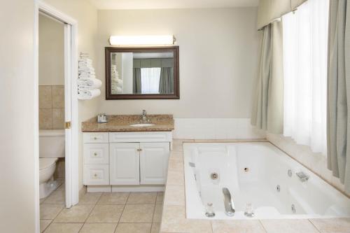 a white bathroom with a tub and a sink at Travelodge by Wyndham Golden Sportsman Lodge in Golden