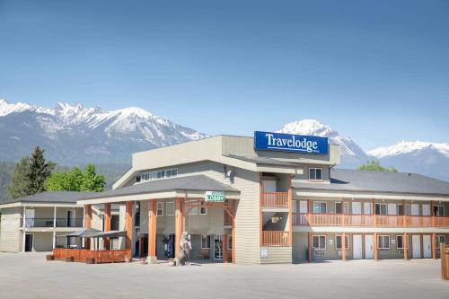 a hotel with snow covered mountains in the background at Travelodge by Wyndham Golden Sportsman Lodge in Golden