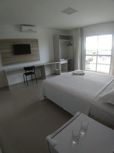 a bedroom with a bed and a desk and a window at Premium Hotel in Mombaça