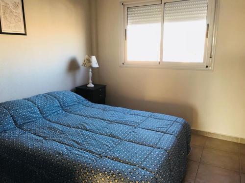 Un dormitorio con una cama azul y una ventana en Hermoso apartamento a pasos de BV Pellegrini cochera! en Santa Fe