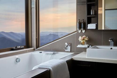 baño con bañera, lavabo y ventana en Breathtaker Hotel and Spa en Mount Buller