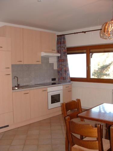 a kitchen with white cabinets and a table and a dining room at Gasthof Majestic in Bressanone