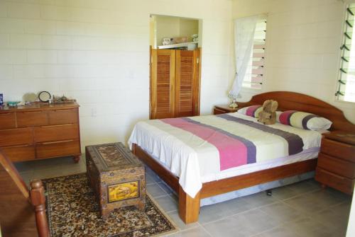 a bedroom with a bed and a dresser with a teddy bear on top at Samoan Highland Hideaway in Siusega