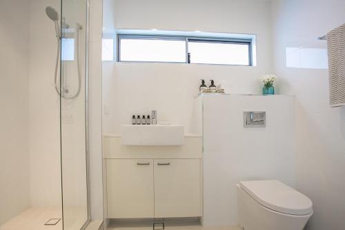 a white bathroom with a toilet and a sink at 10 Hastings Street Motel in Noosa Heads