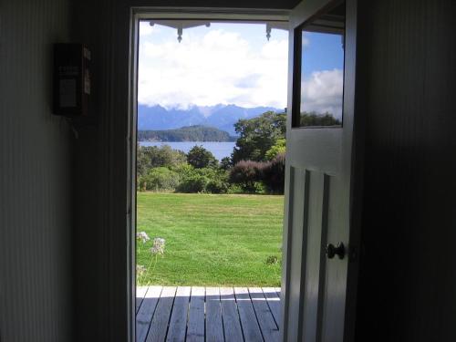 an open door with a view of a field at Murrells Grand View House in Manapouri