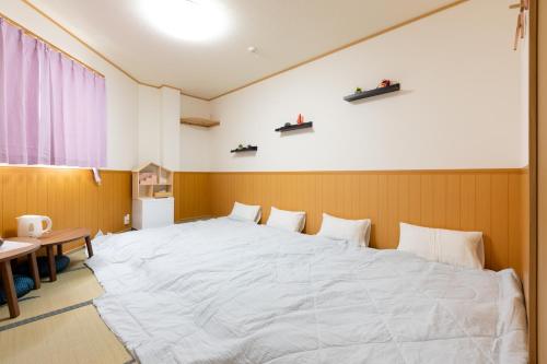 泉佐野市にあるABC ゲストハウスのテーブル付きの客室で、白い大型ベッド1台が備わります。