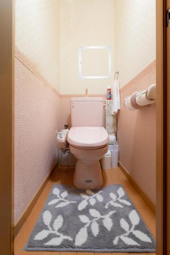 a small bathroom with a toilet and a rug at ABC Guest House 2F in Izumi-Sano