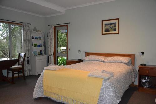 a bedroom with a bed and a table and a window at Treetops B&B in Portobello