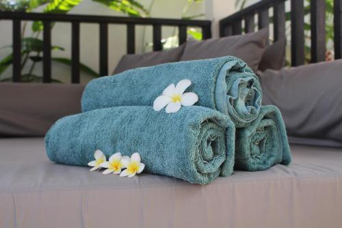 una pila de toallas con flores en una cama en Villa Pemaron, en Lovina