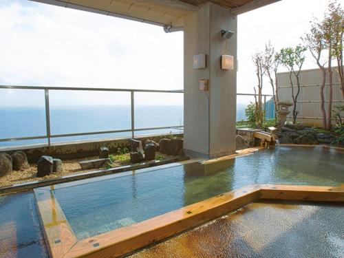 a swimming pool with a view of the ocean at Itoen Hotel Atagawa in Higashiizu
