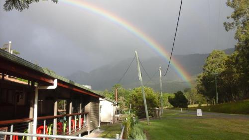 a rainbow in the sky over a building and a house at Christmas Creek Café & Cabins in Lamington