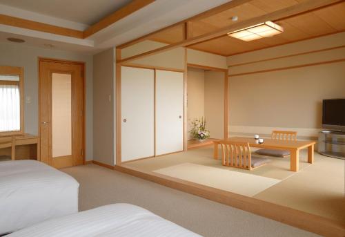 a room with a bed and a table and a tv at Toba International Hotel in Toba