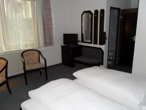 a bedroom with two beds and a chair and a mirror at Hotel Gasthof Traube in Kernen
