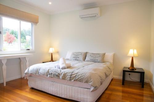 a white bedroom with a bed and two lamps at Lithgow Falls Marysville in Marysville