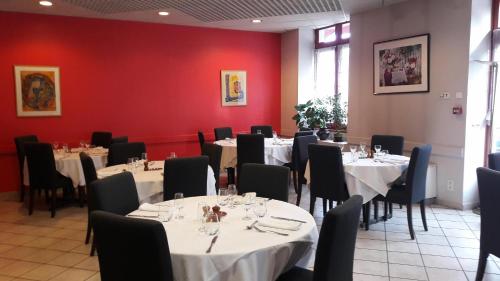 une salle à manger avec des tables, des chaises et des murs rouges dans l'établissement Logis Hotel du Parc-Restaurant - Le Rouget de Lisle, à Lons-le-Saunier