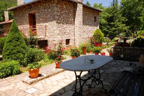 a table in front of a stone building with plants at Andrea Sofi Guesthouse in Dhimitsana