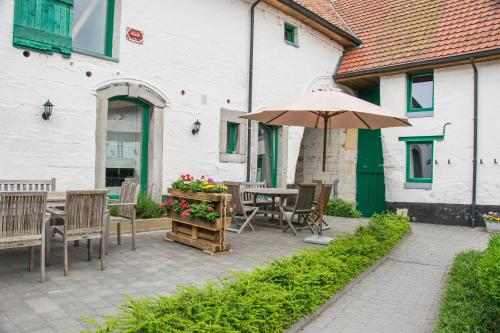 a patio with a table and chairs and an umbrella at B&B De Oude Winning in Riemst