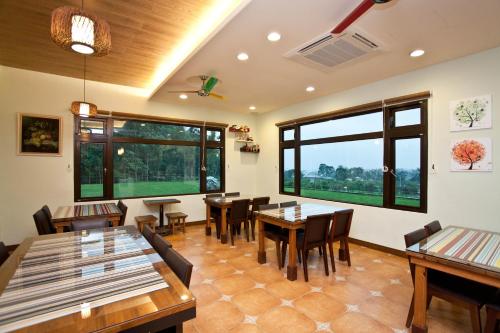 ein Restaurant mit Tischen und Stühlen und großen Fenstern in der Unterkunft Li Wu Zuo Cun B&B in Chongde