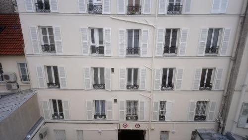 un edificio de apartamentos con puertas y ventanas blancas en Meublés de Tourisme à Vincennes en Vincennes
