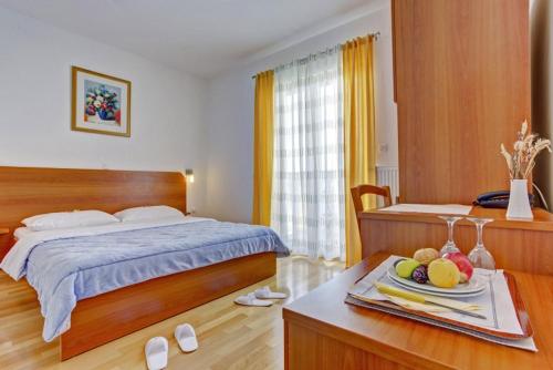 ein Schlafzimmer mit einem Bett und einem Tisch mit einem Tablett mit Obst in der Unterkunft Pansion Villa Bok in Novalja