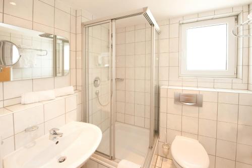 a white bathroom with a sink and a shower at Hotel Schützenburg in Burscheid
