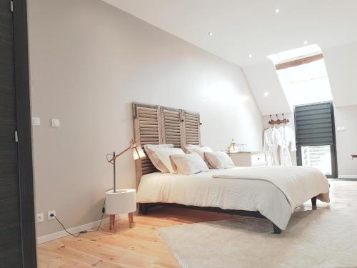 a white bedroom with a large bed with white pillows at Domaine du bois Chaumet in Couzon