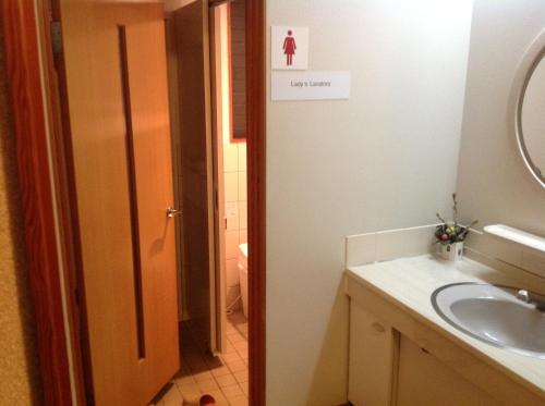 a bathroom with a sink and a toilet and a mirror at Nakayasu Ryokan in Kanazawa