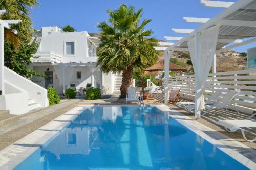 a swimming pool with chairs and a white house at Alexandros Village in Adamantas