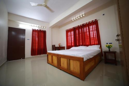 1 dormitorio con 1 cama grande y cortinas rojas en Indeevaram Residency, en Trivandrum