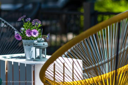 a table with a vase of purple flowers on it at Orbisa Pokoje i Apartamenty in Łeba