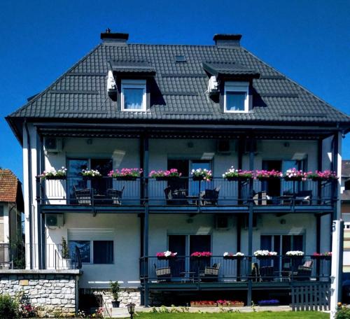 una casa grande con balcones y flores. en Enjoyit Rooms en Velden am Wörthersee