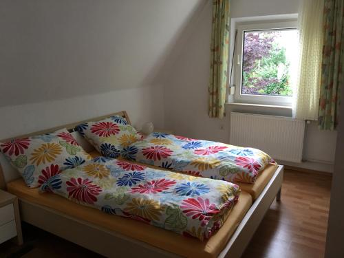 a bed with colorful sheets on it with a window at Das Steghaus in Gräfenberg