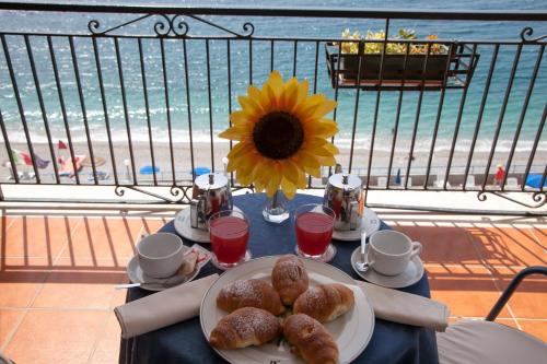 a table with a plate of pastries and a sunflower at Park Hotel Silemi in Letojanni