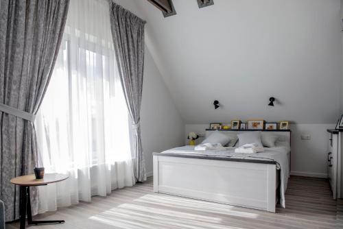 a white bedroom with a bed and a large window at Karkle Twins in Karklė