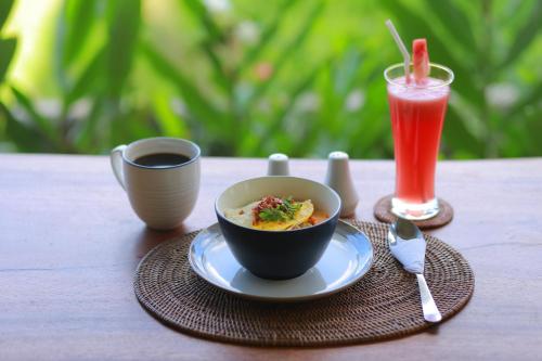 a bowl of food on a table with a drink at Nirwa Ubud Karma in Ubud