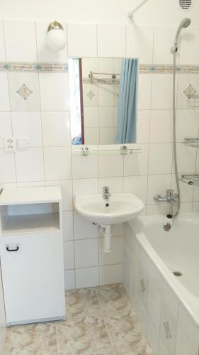 ein weißes Badezimmer mit einem Waschbecken, einer Badewanne und einem Waschbecken in der Unterkunft Zelený Apartment in Růžová