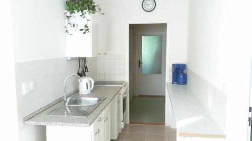 eine weiße Küche mit einem Waschbecken und einer Uhr an der Wand in der Unterkunft Zelený Apartment in Růžová