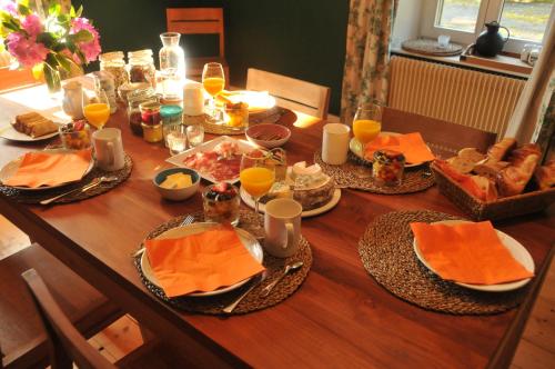 a wooden table with food and orange napkins and orange dishes at s'YVOUX plaît in La Chapelle