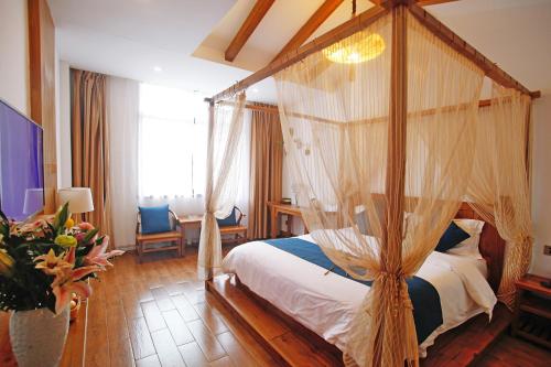 ein Schlafzimmer mit einem Himmelbett in einem Zimmer in der Unterkunft Guihua Road 106th Hostel in Zhangjiajie