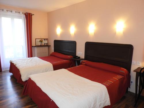 a hotel room with two beds and a window at Logis Hôtel Restaurant de la Poste in Tarascon-sur-Ariège