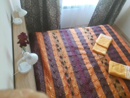 a bedroom with a bed with a purple and orange quilt at Couple getaway to a freshly renovated apartment in Pärnu