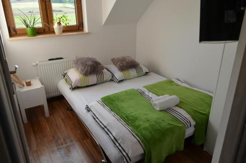 カシナ・ビエルカにあるPokoje na Wzgórzuの小さなベッドルーム(緑のシーツと枕が備わるベッド付)
