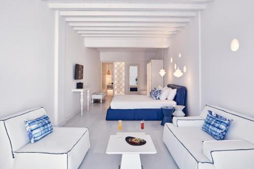 a white room with a bed and two white couches at Katikies Mykonos - The Leading Hotels of the World in Agios Ioannis Mykonos